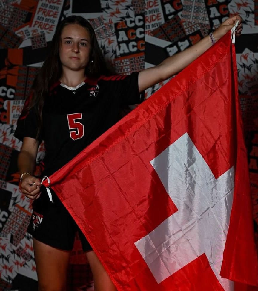 Une joueuse de soccer en maillot noir numéro 5 tient un drapeau suisse lors d'une séance photo d'équipe universitaire